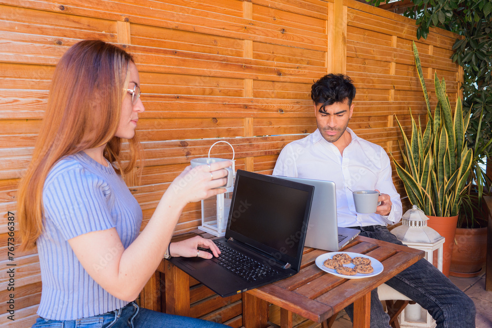 Woman and man working on laptop at rustic wooden patio during daytime Woman and man working on laptop at rustic wooden patio during daytime