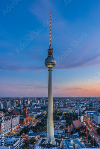 Television tower in the center of the city of Berlin. Sunset with few clouds. Illuminated street and buildings at Alexanderplatz. Landmark of the capital of Germany in the evening at blue hour
