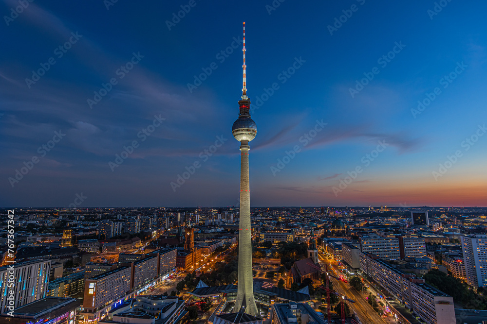 Fototapeta premium Evening mood of the Berlin skyline at the blue hour. Illuminated television tower at Alexanderplatz in the center of the capital of Germany. Illuminated buildings and streets with the Red Town Hall
