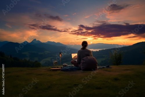 Digital Nomad Lifestyle with Mountain View. Woman working on laptop outdoors, enjoying a majestic mountain landscape at twilight.