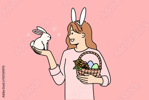 Teenage girl celebrating easter holds decorated eggs in basket and small rabbit, rejoicing at coming of spring. Schoolgirl is preparing for easter and bringing traditional gifts to friends from school