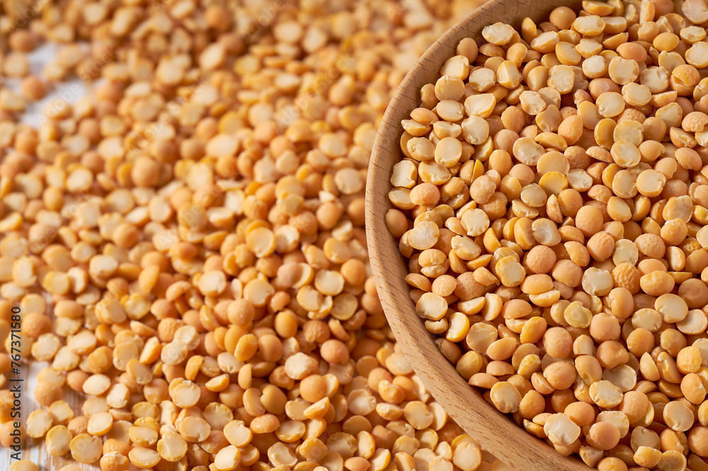 Organic raw dried peas are scattered in a wooden bowl close up. Organic raw dried peas are scattered in a wooden bowl close up.