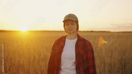 A woman agronomist stands in a field with a tablet, looking at the land