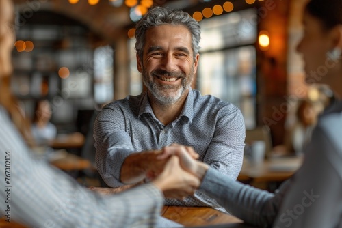 Businessman and business partner shaking hands with a warm smile in a cozy cafe setting photo