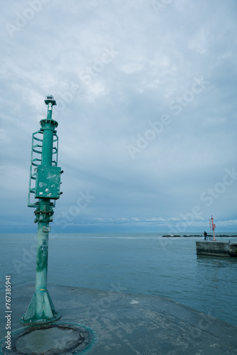 Port and pier equipment, little beacon on the pier in a Riviera Romagnola beach location. dramatic sky in a winter afternoon. Winter sea. Moody and gloomy day.