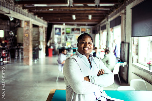 Young man of african ethnicity looking at the camera with crossed arms while working in a startup company office