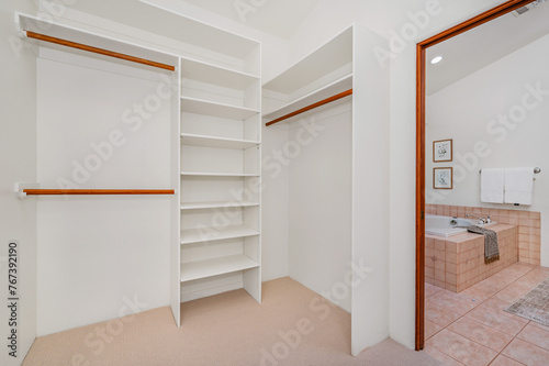 an empty walk in closet and tub with shelves in the corner