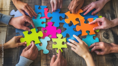 Close-up of human hands connecting jigsaw colorful puzzle pieces on wooden table. Teamwork concept.