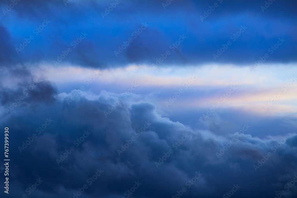 Blue clouds in the sky and a strip of light on the horizon, sky with blue clouds and sunlight in the distance