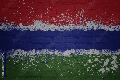 colorful painted big national flag of gambia on a massive brick wall