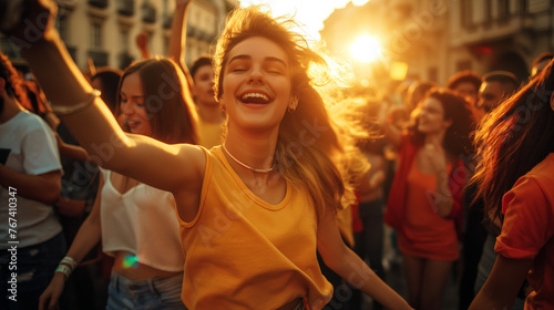 A joyful crowd of young people dancing and celebrating in a city square, surrounded by historic architecture, the scene bathed in the golden hour light that enhances their diverse