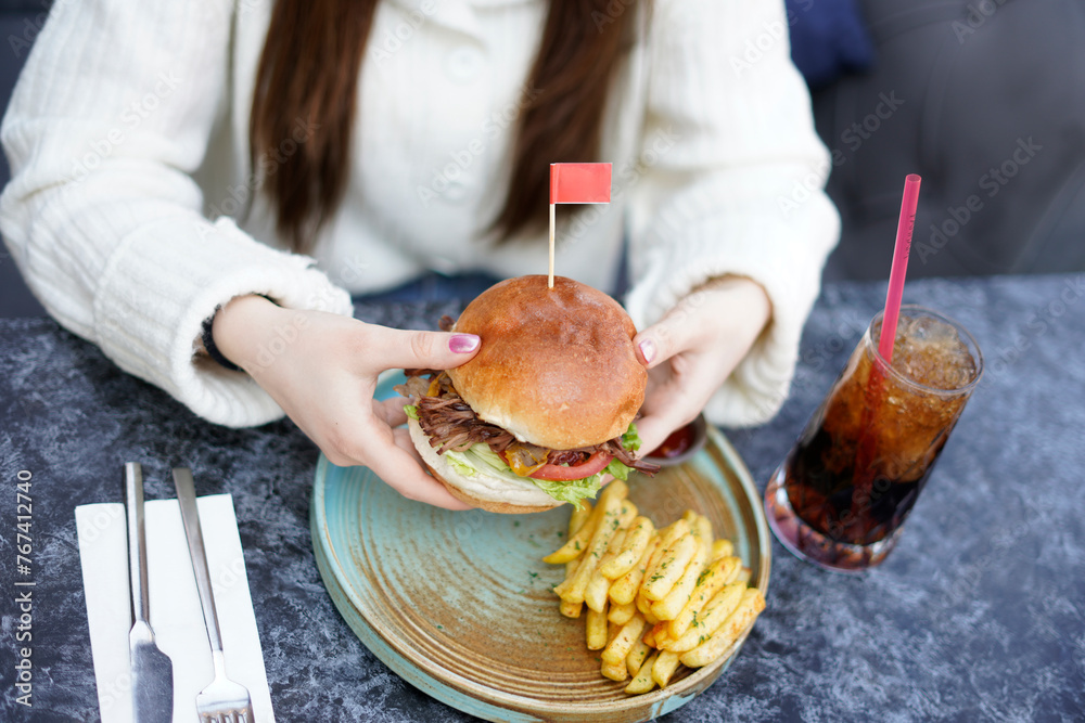 Beautiful woman holding hamburger. Cafe product shooting for advertising purposes