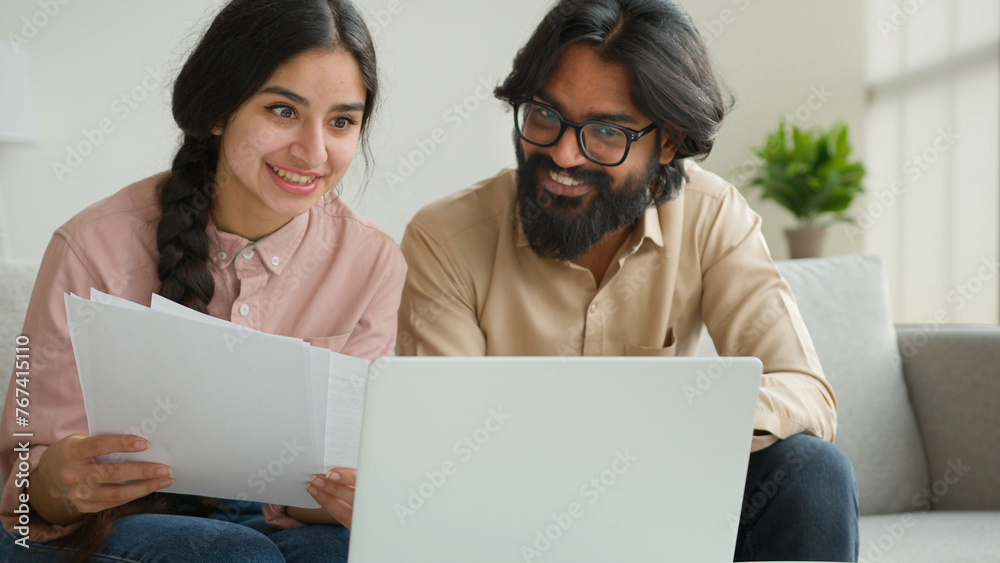 Arabian couple homeowners read tenancy papers at home paying domestic bills taxes online on laptop multiethnic woman and man planning budget talking discuss documents loan payments bank house mortgage Arabian couple homeowners read tenancy papers at home paying domestic bills taxes online on laptop multiethnic woman and man planning budget talking discuss documents loan payments bank house mortgage