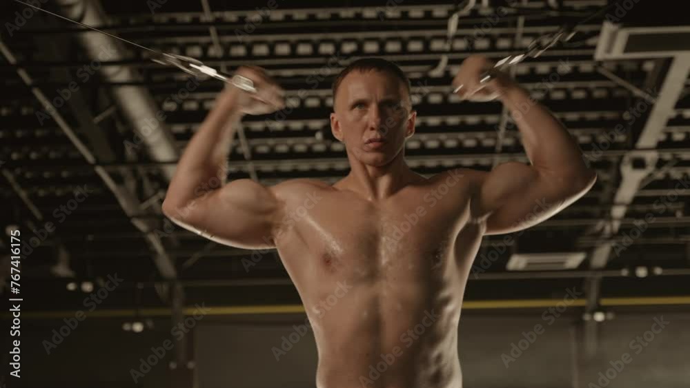 Barechested bodybuilder in shorts, working out his muscles on a gym bar Barechested bodybuilder in shorts, working out his muscles on a gym bar