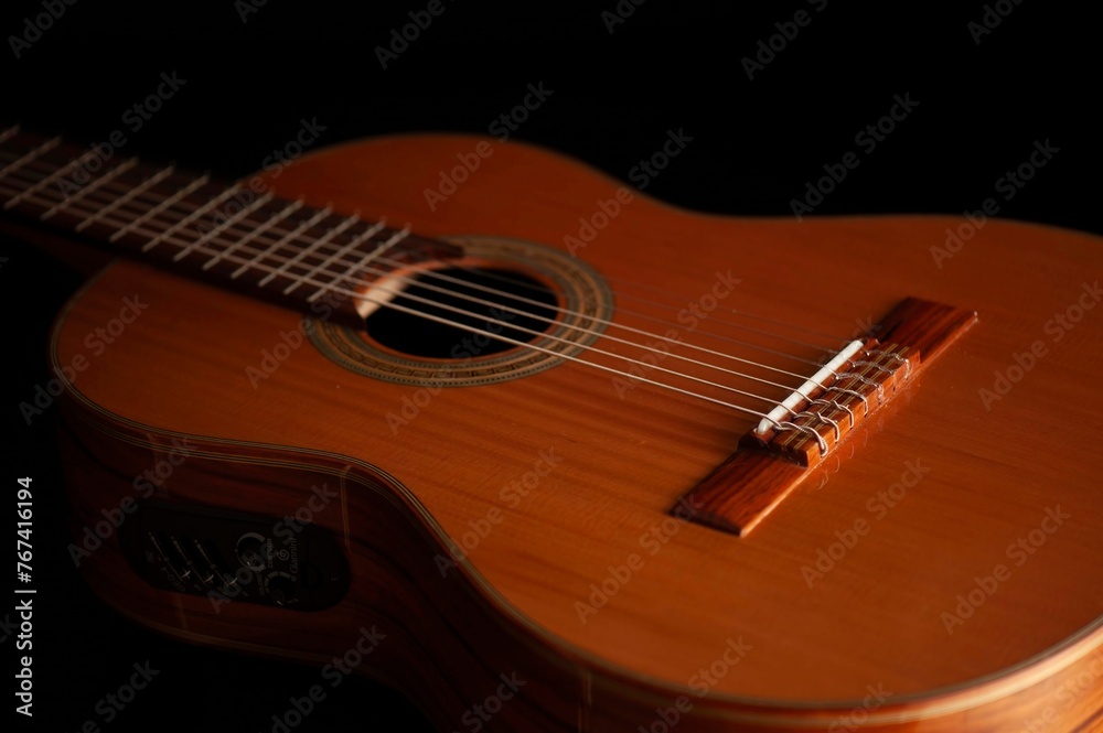 Fototapeta premium Classical Spanish flamenco guitar close up, dramatically lit isolated on black background with copy space.