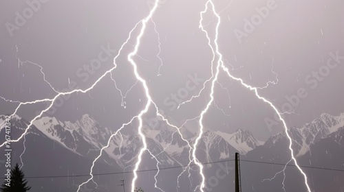  a large group of lightning strikes in the sky over a snow covered mountain range with power lines in the foreground.