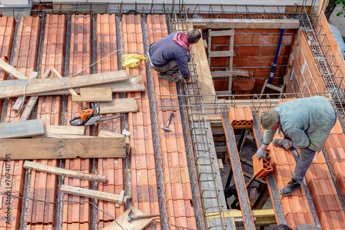 Construction workers arrange the building bricks before pouring the roof slab. Fabricating the timber formwork and installing the steel reinforcement bar.