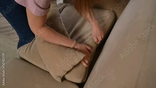 A young woman looks for car keys on the sofa and ends up finding them under the pillow. Live camera, active motion photo