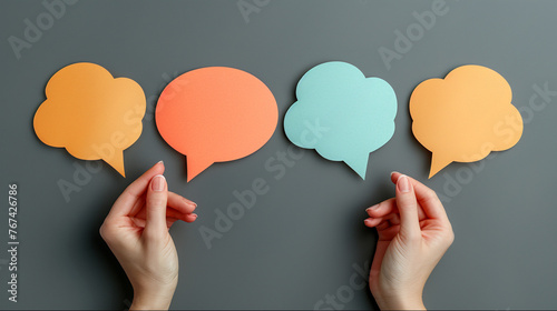 Colorful paper speech bubbles with hands isolated on grey background.
