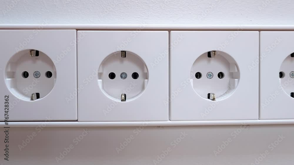 Close-up of three european standard electrical outlets in a row on a white wall