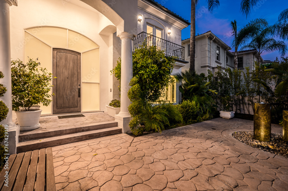 Naklejka premium Illuminated stone path and stairs leading to a house entrance at sunset