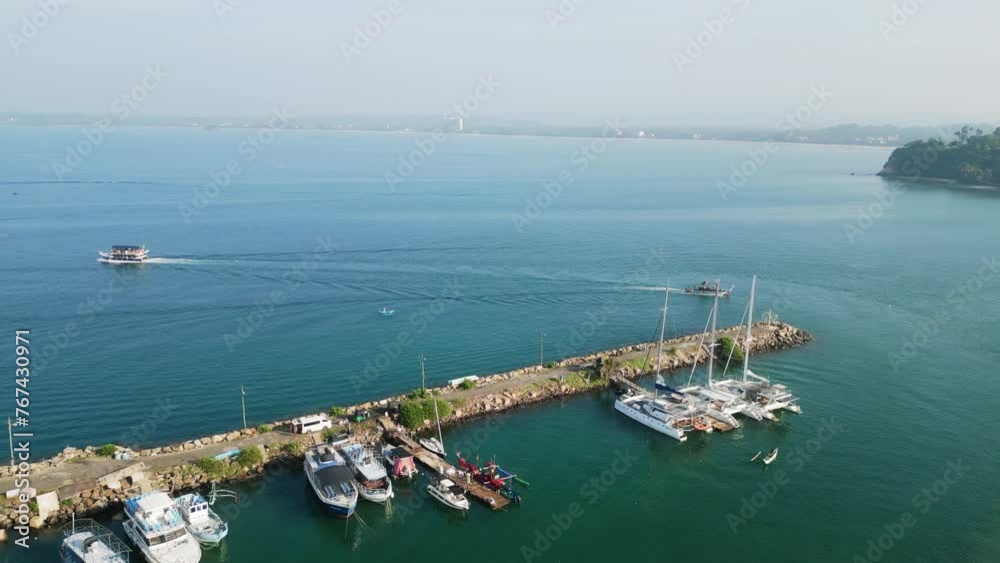Aerial of Mirissa harbor displays yachts for rent, perfect setting for sailing vacations. Drone clear skies, calm blue ocean with marine vessels docked. For travel promos, nautical lifestyle content. Aerial of Mirissa harbor displays yachts for rent, perfect setting for sailing vacations. Drone clear skies, calm blue ocean with marine vessels docked. For travel promos, nautical lifestyle content.