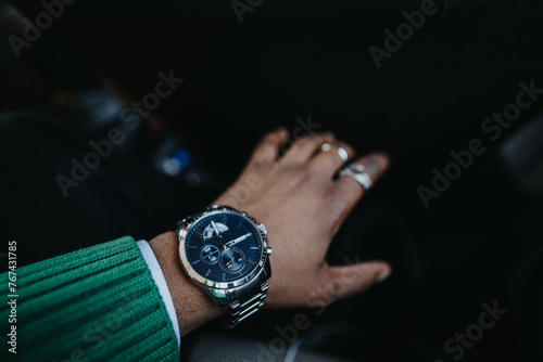 Close-up of a business person's hand with a stylish watch inside a car, symbolizing time management and punctuality in corporate lifestyle.