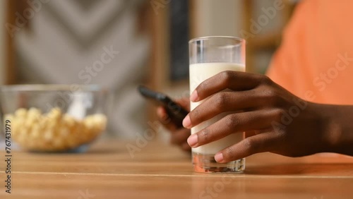 Close-up of a black guy's hand taking a glass of milk from the table and then putting it back
