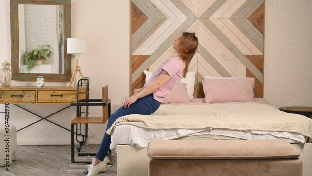 Young woman falls back on the bed with a smile, slow motion