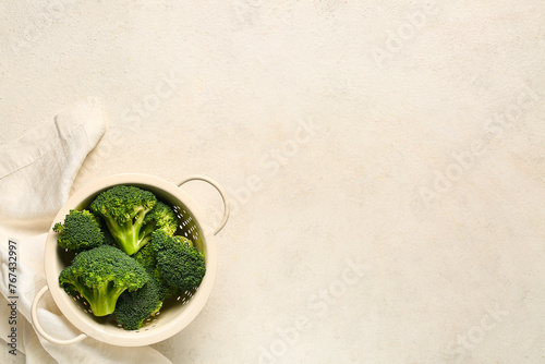 Colander with fresh broccoli cabbages on white background