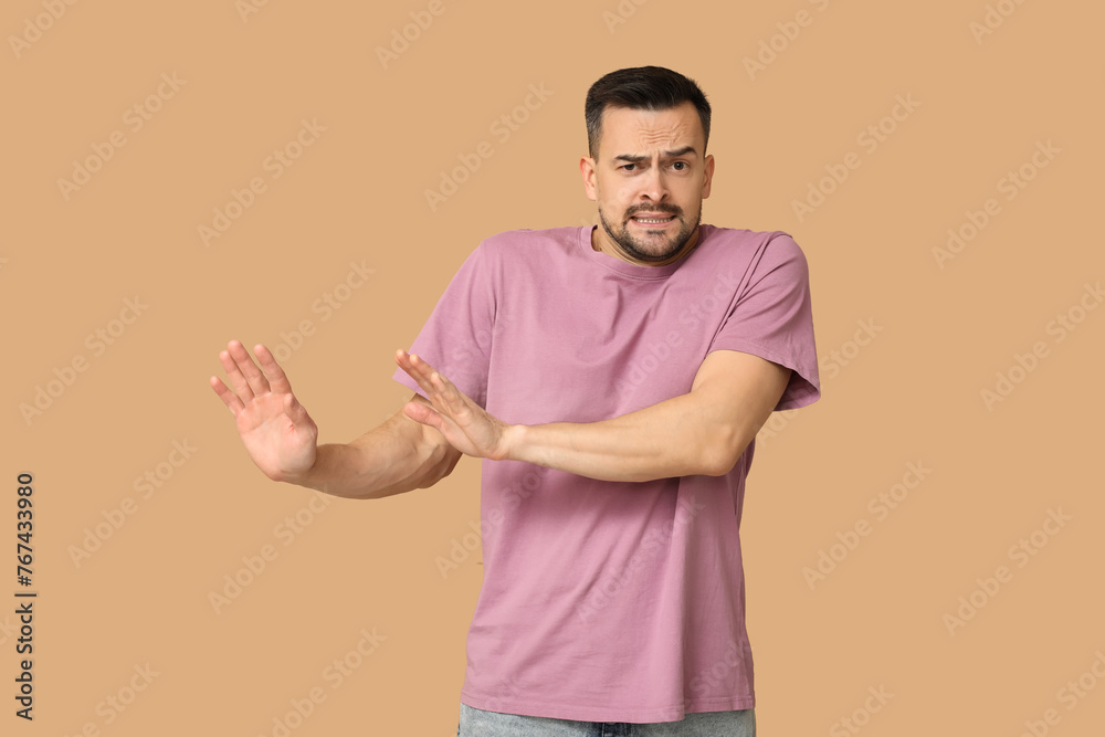 Handsome ashamed young man on brown background - obrazy, fototapety, plakaty 