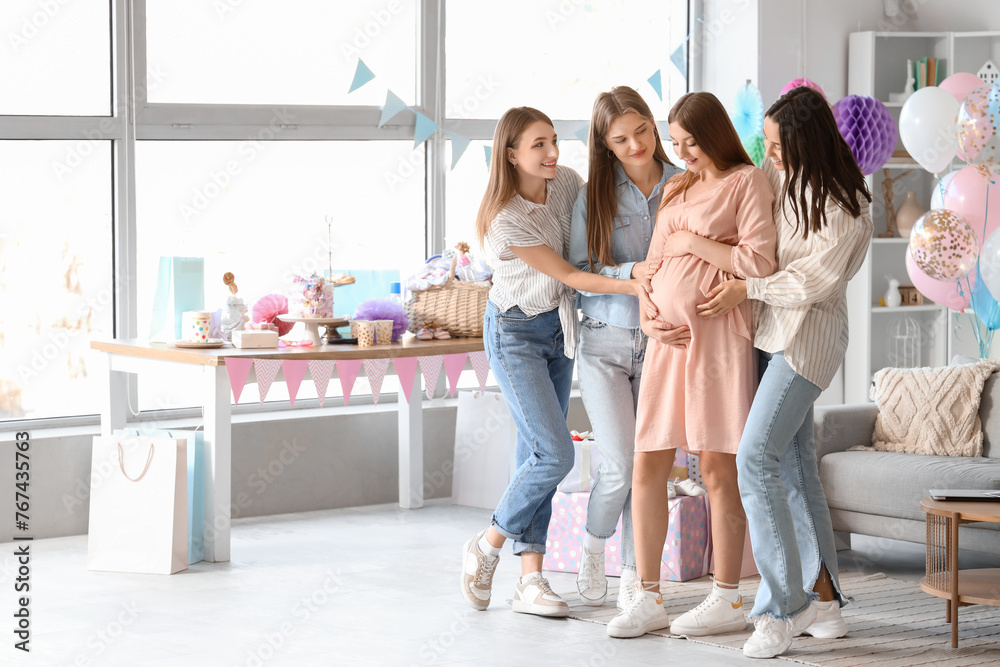 Female friends touching belly of young pregnant woman at baby shower party Female friends touching belly of young pregnant woman at baby shower party