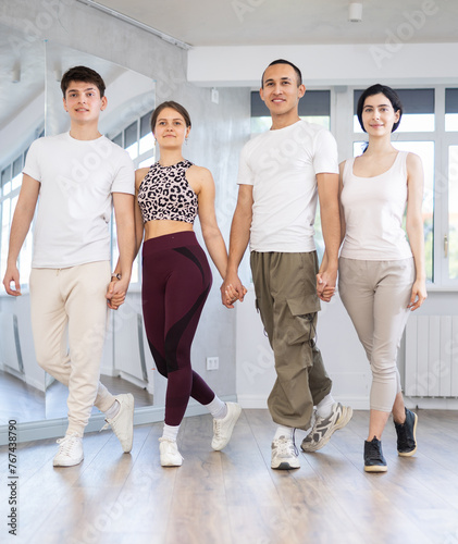 Smiling young multinational men and women dancing catalan typical Sardanas in modern dance salon photo