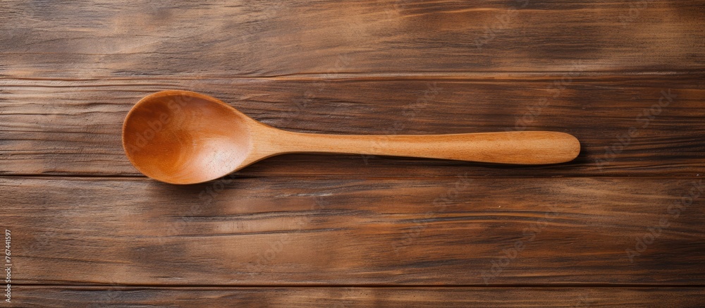 A simple image featuring a wooden spoon placed on a plain wooden table surface A simple image featuring a wooden spoon placed on a plain wooden table surface