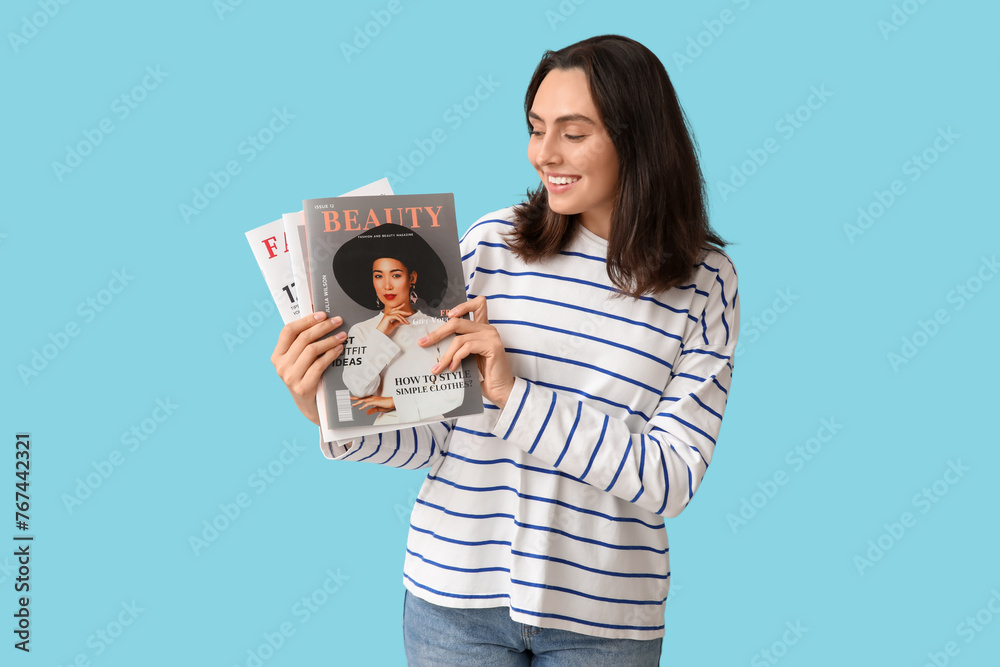Smiling young woman with magazines on blue background Smiling young woman with magazines on blue background