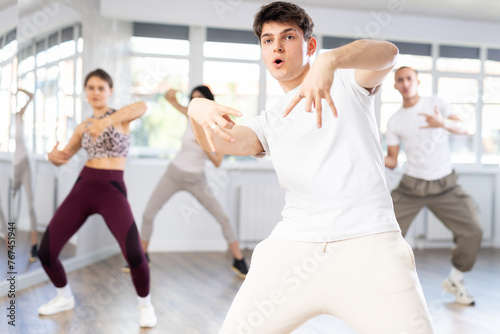 Group of young people  girls and guys in sportive casual style clothes dancing in choreography class