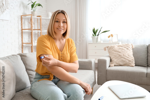 Diabetic woman using lancet pen at home