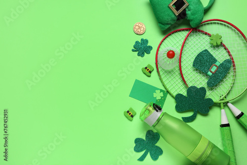 Water bottle, badminton rackets and decorations for St. Patrick's Day celebration on green background