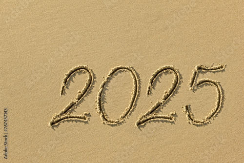 Drawing sun and 2025 on the sandy beach of the coastline as a symbol of the beach season