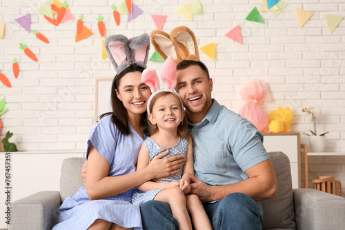 Happy family in Easter bunny ears sitting on sofa at home © Pixel-Shot