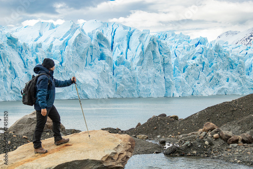 Homem com mochila caminhando e explora geleira azul na Patagônia. photo