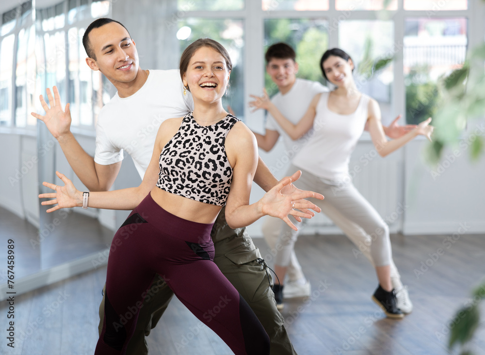 Fototapeta premium Couple of young guy and young woman dancing twist in studio