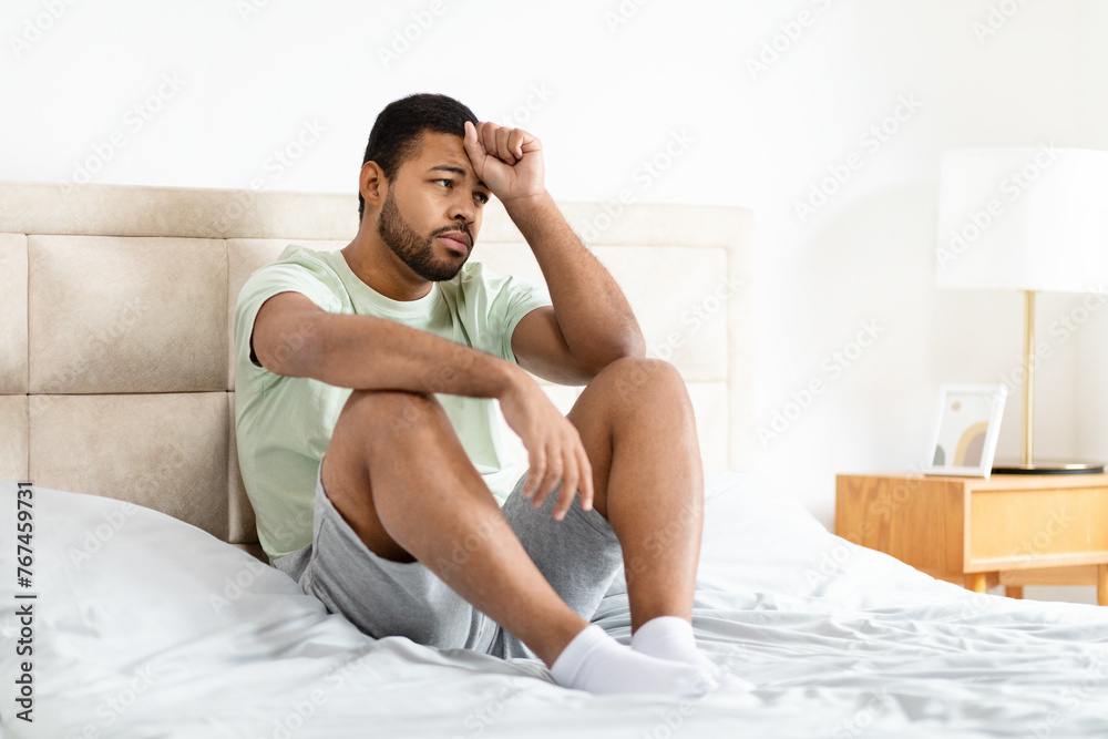 Man sitting on bed looking thoughtful Man sitting on bed looking thoughtful