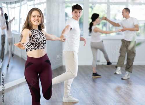 Couple of young guy and young woman dancing twist in studio