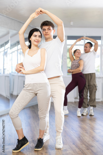 Young couple learns to dance pair disco fox during dance class in studio, repeat movements and learn act show. Studio school for amateur and professional dancers