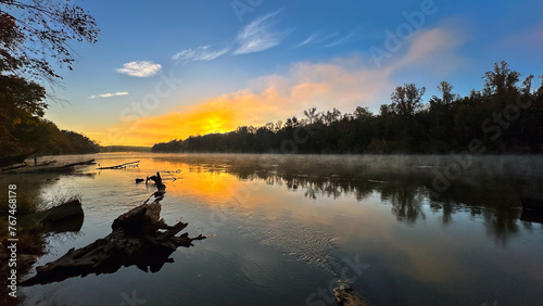 Blazing sunrise over river with morning mist #767468178