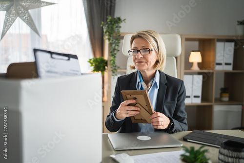 Mature woman lost her job fired from work pack personal items in box photo