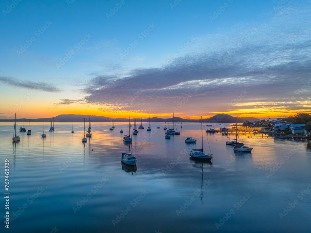 Sunrise over the water with boats and reflections