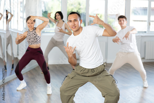 During dance workshop, guy enjoys active dancing, learns new movements, moves synchronously with participants of lesson. Concept of beautiful body through sports, dancing, and active lifestyle