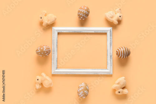 Beautiful composition with frame, bunnies and painted Easter eggs on beige background